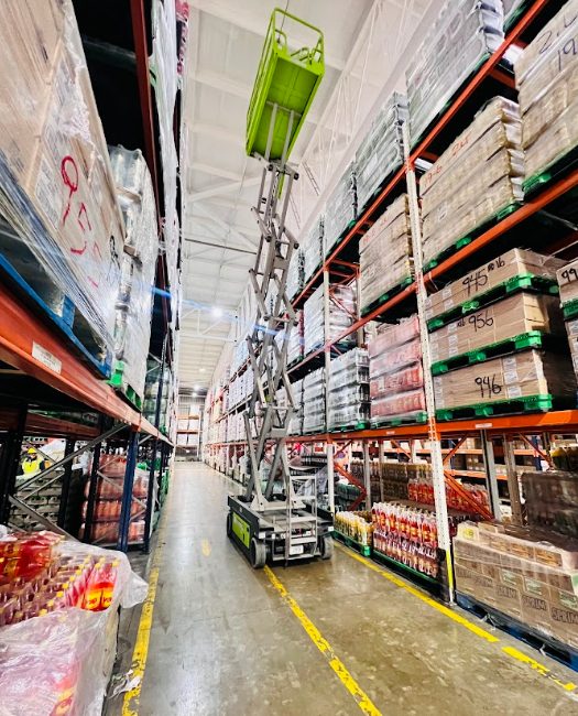 Plataforma tijera elevada en el pasillo de una bodega